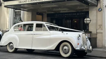 Side view of Classic Austin princess decorated with white wedding ribbons waiting outside Grand Connaught Hotel in London