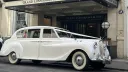 Side view of Classic Austin princess decorated with white wedding ribbons waiting outside Grand Connaught Hotel in London