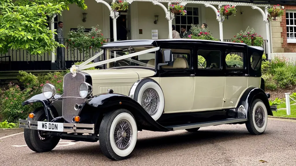 7-seater vintage BRamwith Convertible with White Wall Tires and decorated with white wedding ribbons accross bonnet.
