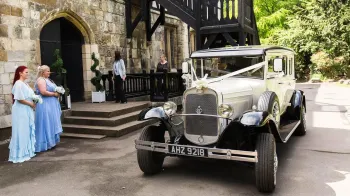 Bride and her Bridesmaid standing next to the Bramwith Wedding Car outside the reception Venue