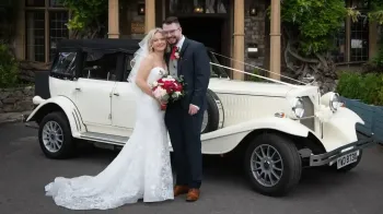 Bride and Groom in front of a Beauford decorated with traditional white ribbons