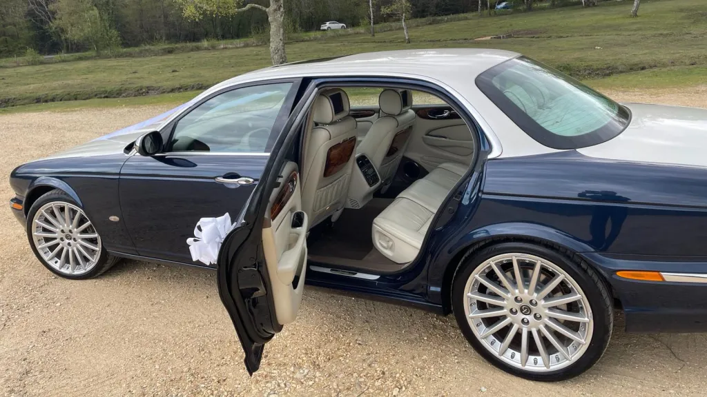 Rear passenger door open showing the cream leather interior seats and wooden table