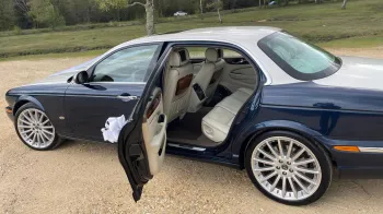 Rear passenger door open showing the cream leather interior seats and wooden table