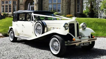 Ivory Beauford Convertible with black soft top roof up dressed with white ribbons across the bonnet