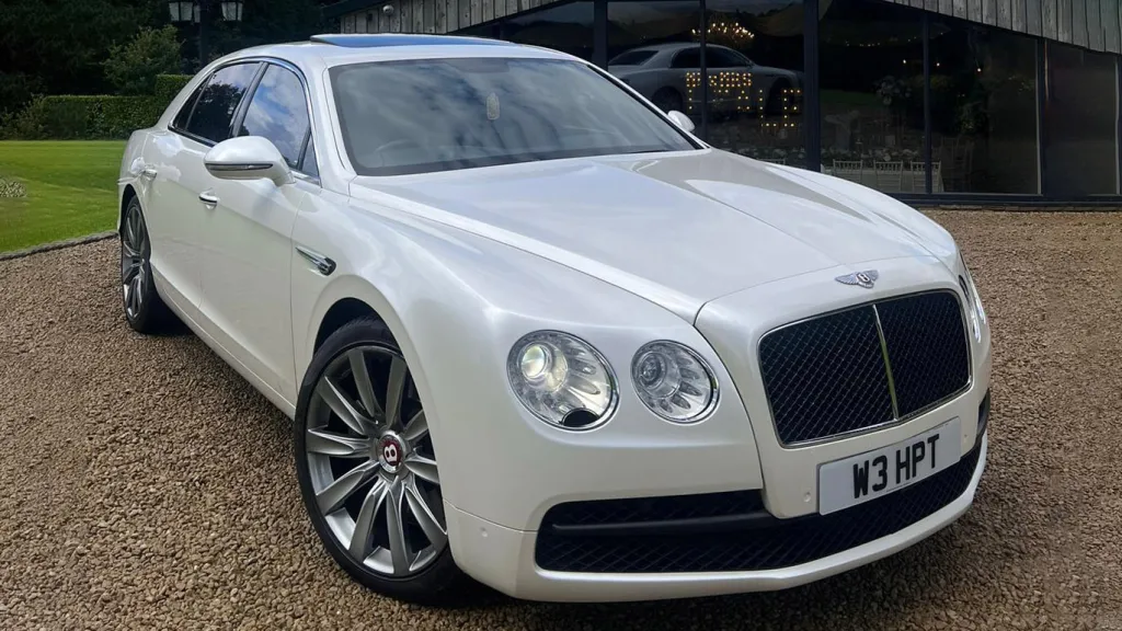 Front side View of White Bentley Flying Spur with large Chrome alloy wheels