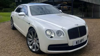 Front side View of White Bentley Flying Spur with large Chrome alloy wheels