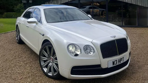 Front side View of White Bentley Flying Spur with large Chrome alloy wheels