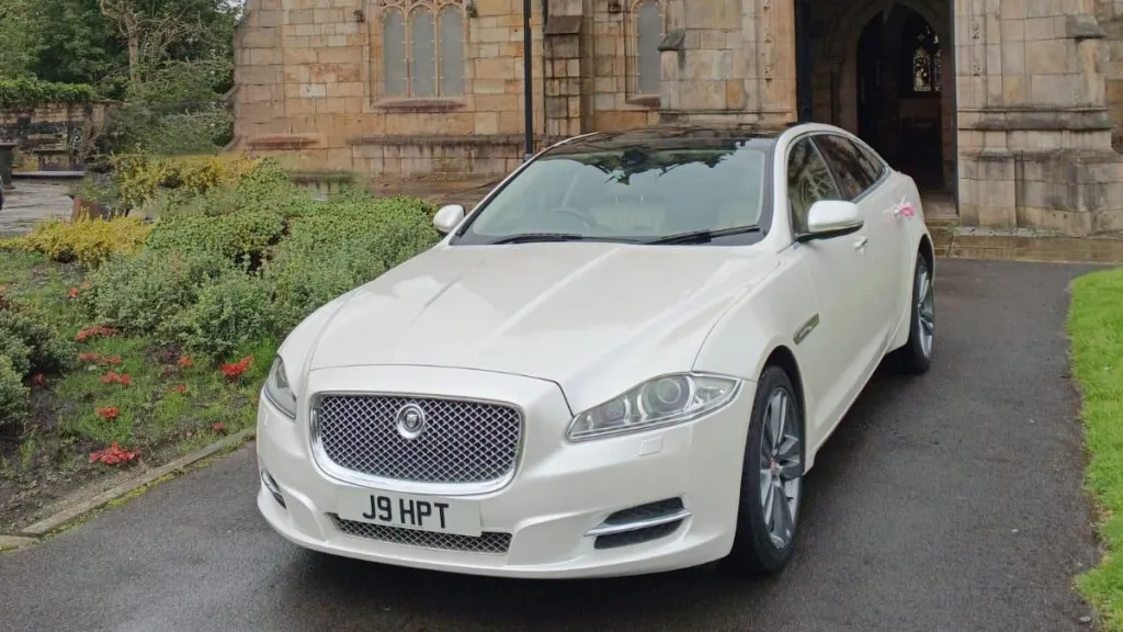 Front View of White Jaguar XJ in front of Wedding Church