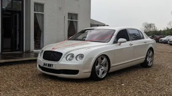 Left Side View of White Bentley Flying spare decorated with a thin Red Ribbon accross its bonnet.