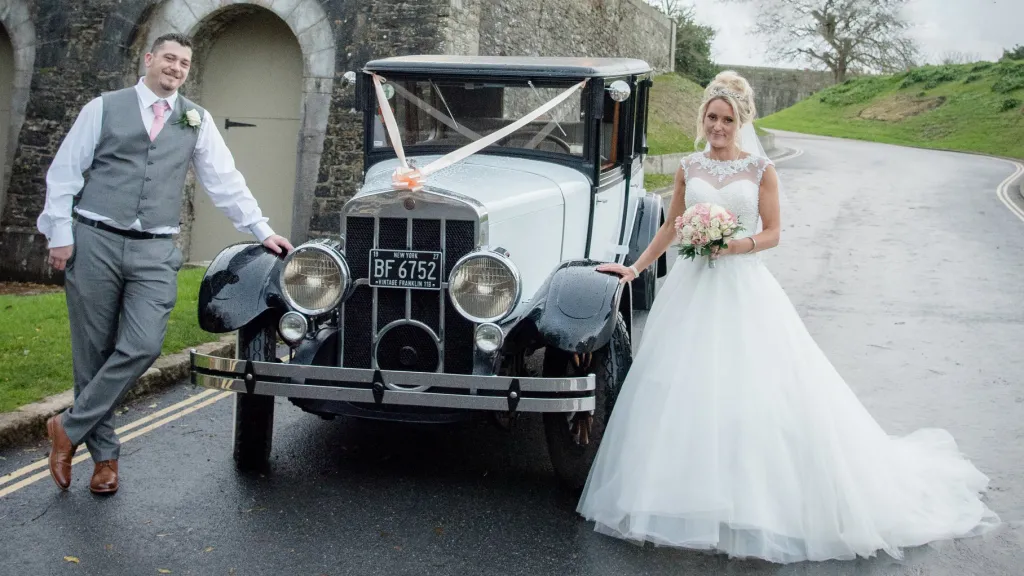 Vintage Franklin with Bride and Groom standing on either side of the vehicle