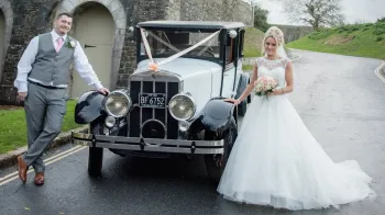 Vintage Franklin with Bride and Groom standing on either side of the vehicle