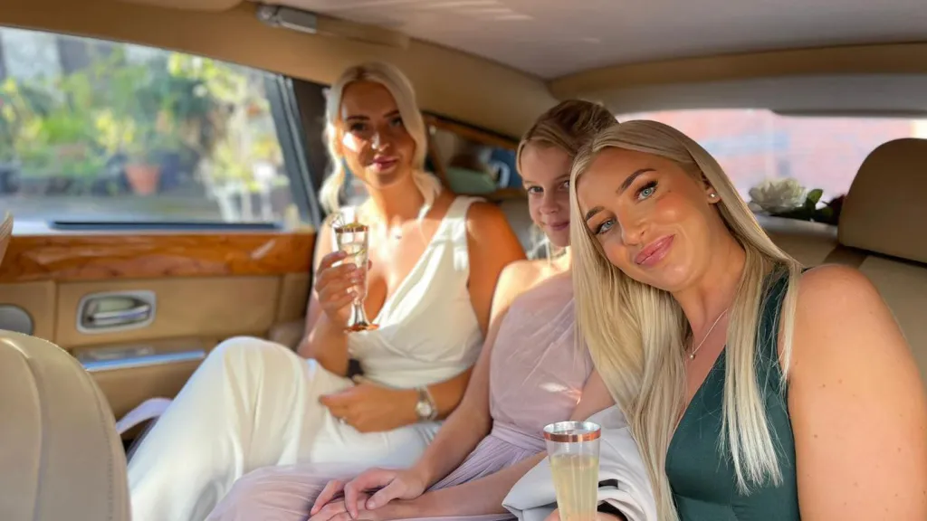 Bride and two bridesmaids seating in the rear of the Rolls-Royde Phantom