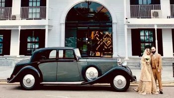 Asian Couple standing next to the vintage Black and Grey Rolls-Royce Phantom