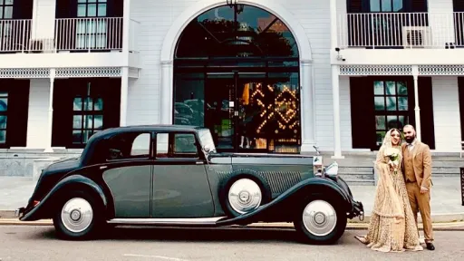 Asian Couple standing next to the vintage Black and Grey Rolls-Royce Phantom