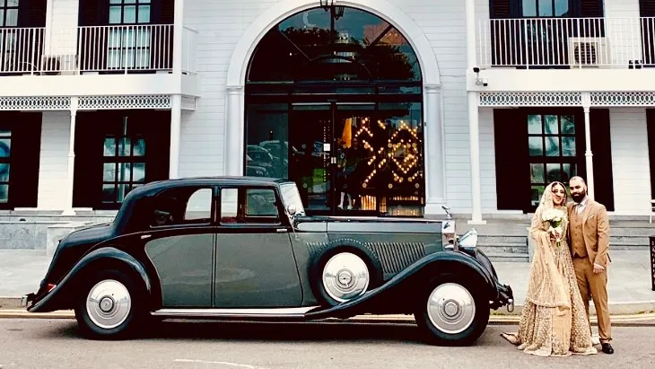 Asian Couple standing next to the vintage Black and Grey Rolls-Royce Phantom