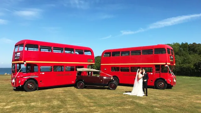 Two Vintage Red Routemaster buses with a vintage Burgundy car in Sherborne. Bride and Groom are standing in front of the vehicles