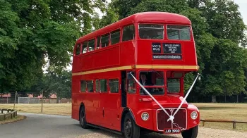 Double Decker Red Routemaster decorated with White ribbons accross the front