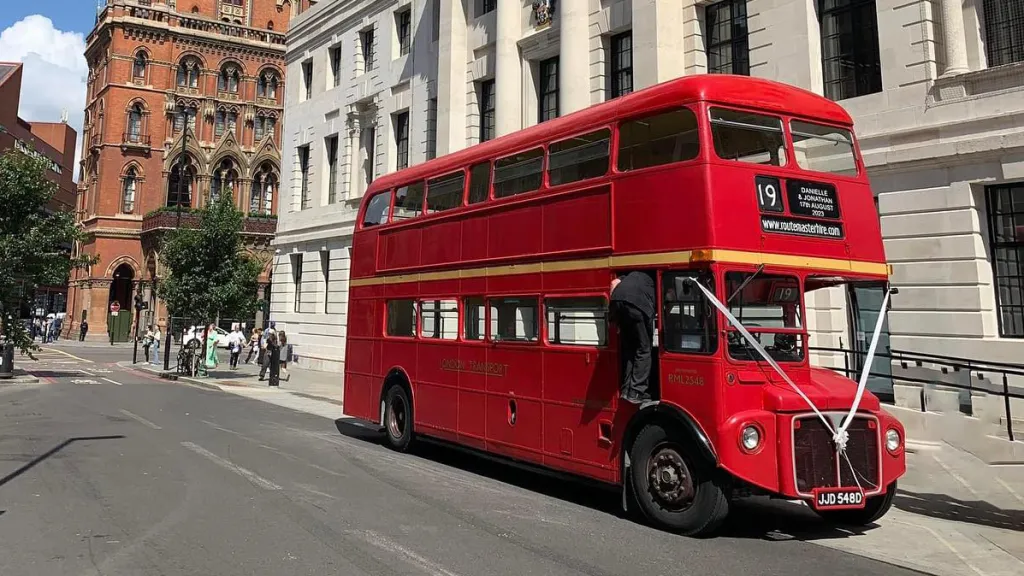 Red Double Routemaster Bus in the street of London with White ribbons accros front