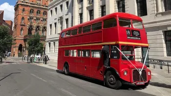 Red Double Routemaster Bus in the street of London with White ribbons accros front