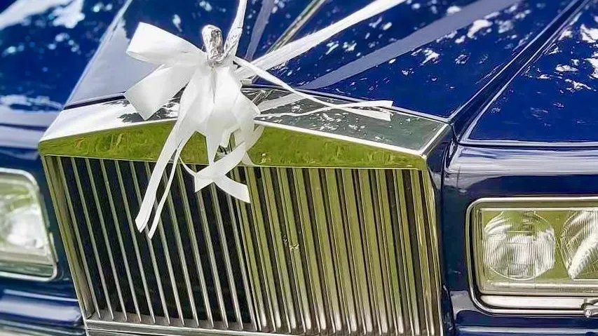White ribbon on a blue rolls-royce silver spur