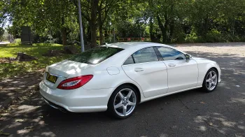 Rear side view of White Mercedes CLA AMG with Green Trees in the background