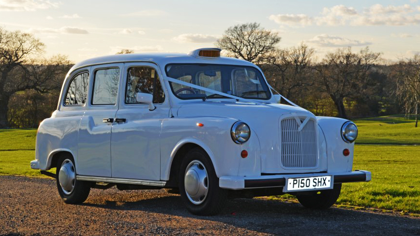 Side view of white classic taxi cab with Orange taxi sign at the top
