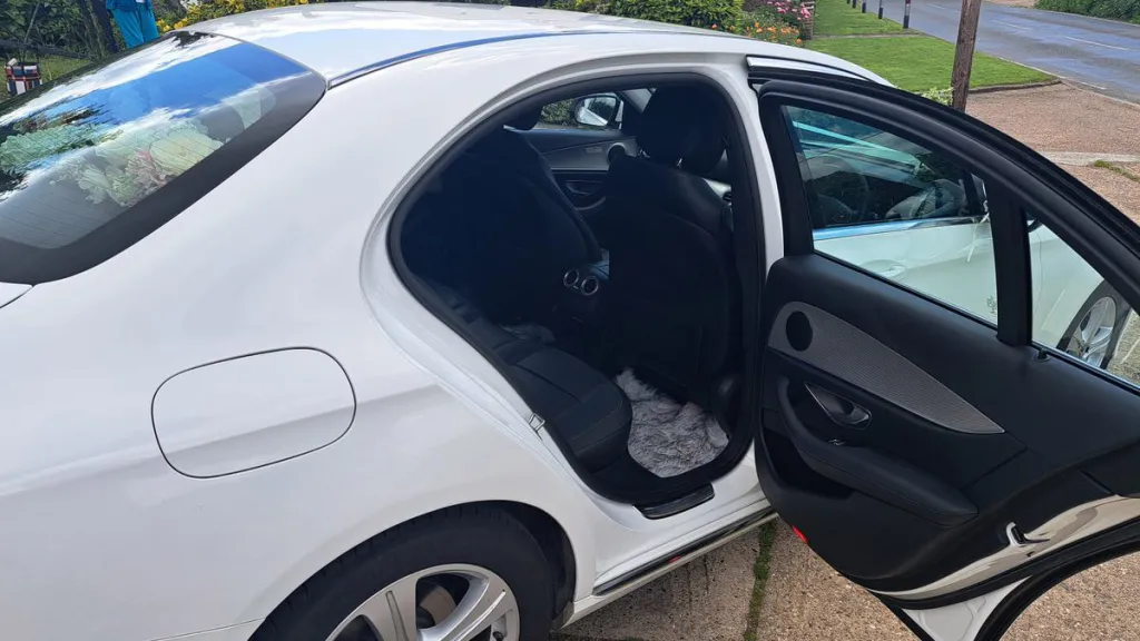 right side rear passenger seating with door open showing black leather seats inside the white mercedes
