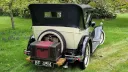 Rear view of Chevrolet with black soft top roof, spare wheel mounted at the rear and a Black and burgungy picnic trunk