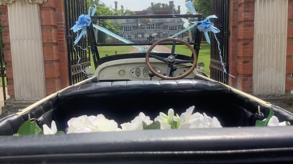 interior of vintage american Chevrolet showing black leather interior, light blue bows and white flowers in the parcel shelf