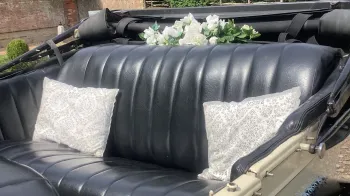 rear interior seats in black leather, white posy of flowers on the parcel shelf and cushions on the rear bench seat