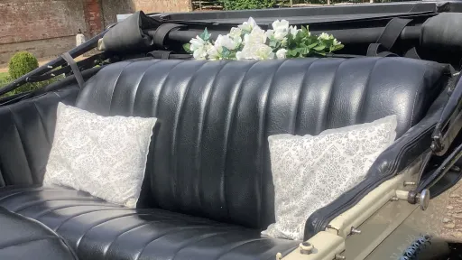 rear interior seats in black leather, white posy of flowers on the parcel shelf and cushions on the rear bench seat