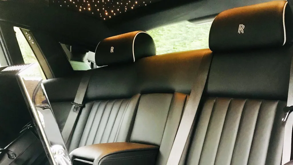 rear interior seating in Rolls-Royce Phantom . Seats are black leather with Rolls-Royce emblem stitched on the headrests