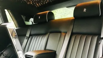 rear interior seating in Rolls-Royce Phantom . Seats are black leather with Rolls-Royce emblem stitched on the headrests