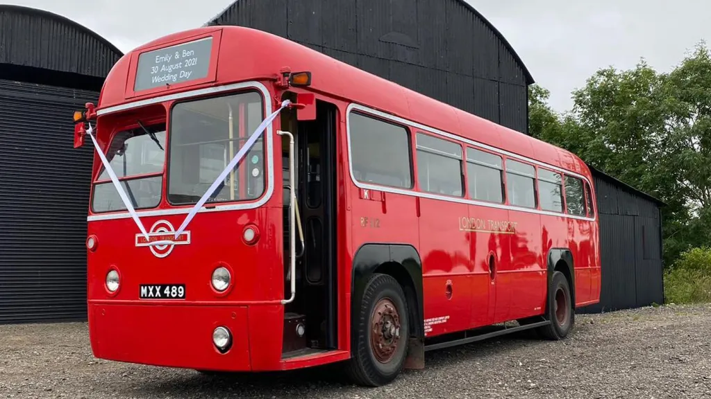 Left side front view of Single Decker Red Bus with white wedding ribbons and front door open