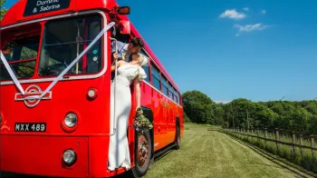 Bride and Groom kissing on the door step of a vintage red bus