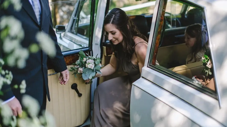 Bridesmaid steping out of classic Daimler limousine