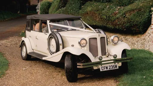 Ivory vintage convertible ribbons with Chocolate brown soft top roof and White ribbons parked on a drive