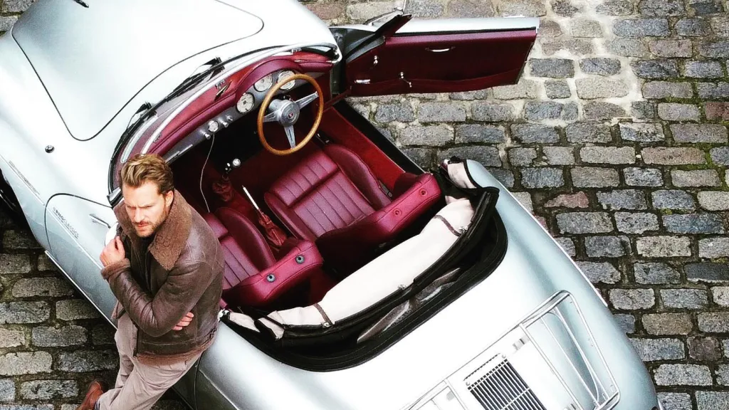 Aerial view of Silver POrsche with convertible roof open showing burgundy leather and driver's door open
