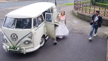 Aerial view of Bride exiting a classic vw campervan in her wedding dress
