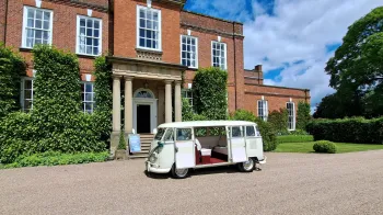 Classic VW campervan parked ion front of wedding venue with large rear door open