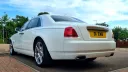 Rear view of White Rolls-Royce Ghost under a bright blue sky