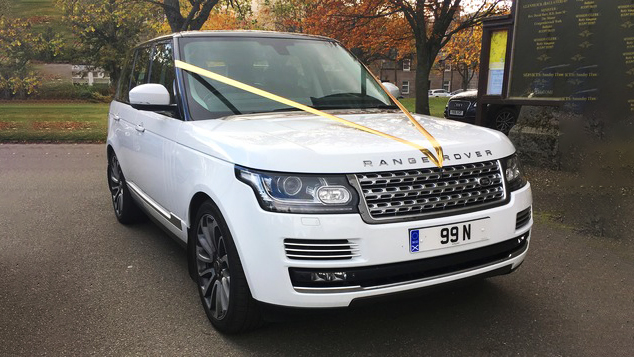 White Range Rover Vogue decorated with yellow ribbons parked in front of a church in Aberdeen