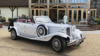 White beauford Convertible with roof down parked in front of a wedding venue.