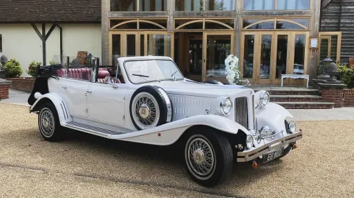 White beauford Convertible with roof down parked in front of a wedding venue.