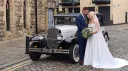 Bride and Groom holding each others n front of black and Ivory Bramwith limousine