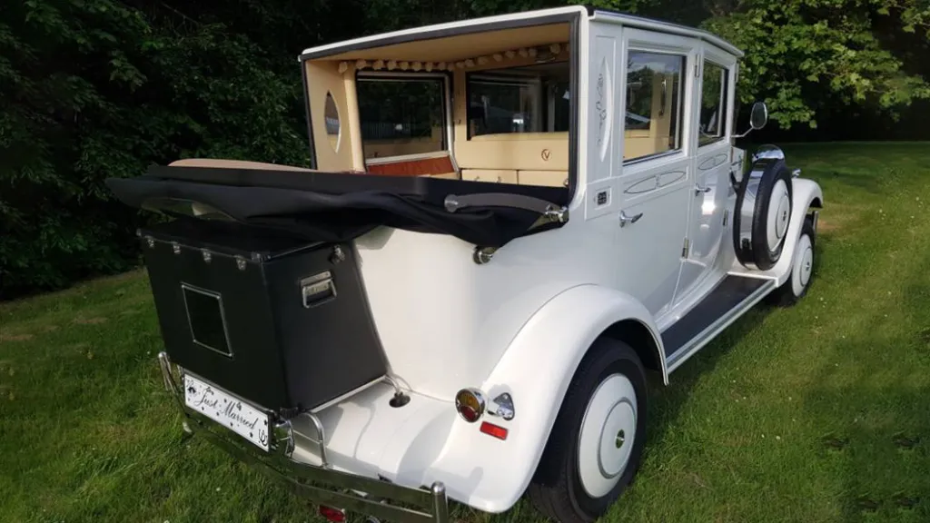 Rear view of White Imperial Convertible wedding car with black soft top roof down and black picnic trunk at the rear