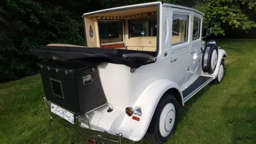 Rear view of White Imperial Convertible wedding car with black soft top roof down and black picnic trunk at the rear