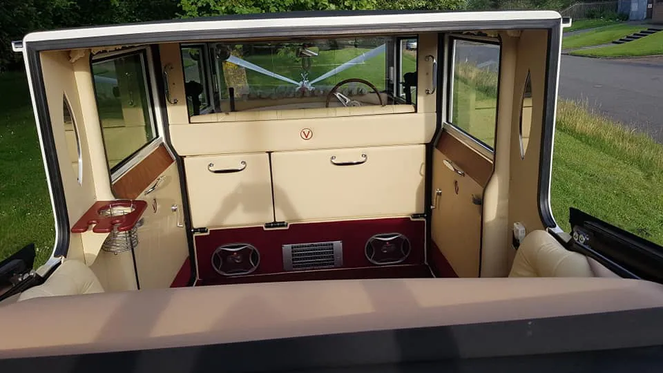White Imperial with convertible roof down showing the rear compartment seating area with cream leather seats and Burgundy carpet