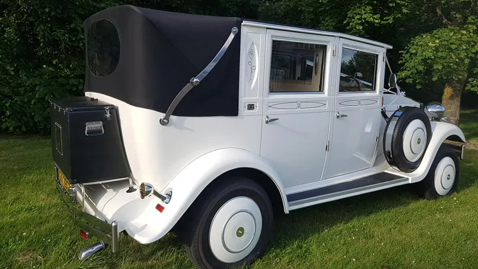 Right rear view of vintage style imperial with black soft top roof closed and spare wheel mounted on the side of the vehicle
