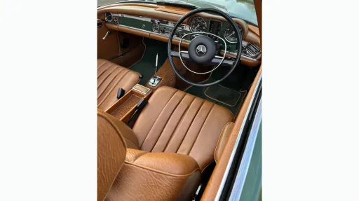 front driver seat and dashboard inside Classic Mercedes 280sl. Seats are Light tan leather with matching colour dashboard.
